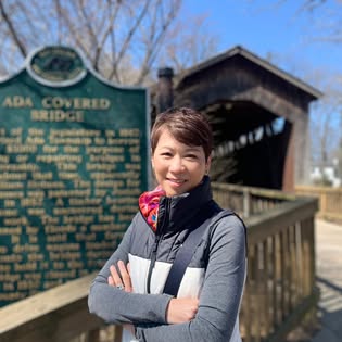 Hui-Fen outdoors beside a historic covered bridge